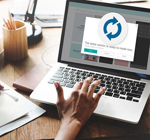 Image of an update happening on a laptop with a hand over the laptop keyboard.